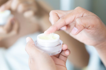 Obraz na płótnie Canvas Close up woman hand applying cream or moisturizer from box for face beauty, selective focus