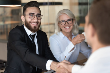 Smiling multiracial business partners handshake closing deal