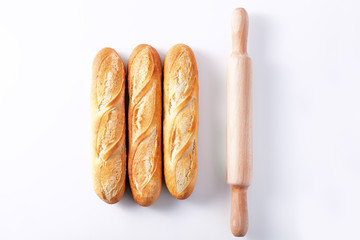 Freshly baked French baguettes on white wooden table.