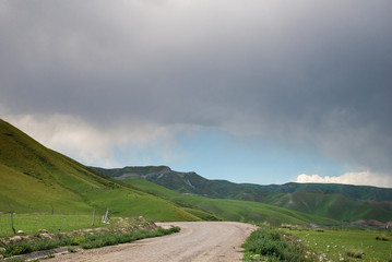 Fototapeta na wymiar Empty rural road in mountains with cloudy sky