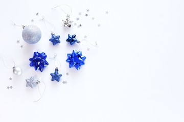 Creative mockup of Christmas decorations, stars and holiday bows. Classic blue colors on a white background. Christmas, New Year, happy holiday concept. Top view, flat lay with copy space for text.