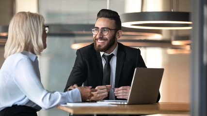 Fototapeta premium Smiling diverse businesspeople discuss ideas at meeting in office