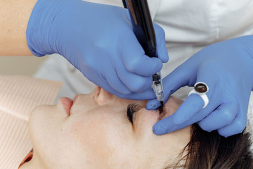 Permanent makeup, tattooing of eyebrows. Cosmetologist applying make up