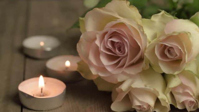 Pink and white blossoming roses with tea light candles