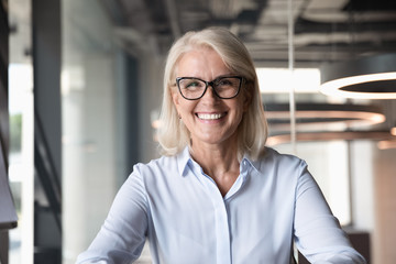 Headshot of middle-aged businesswoman posing at workplace - obrazy, fototapety, plakaty
