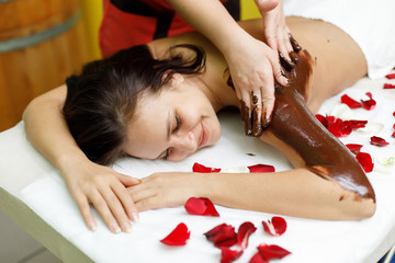 Obraz na płótnie Canvas Masseur applying chocolate to woman's back. Massage in spa salon