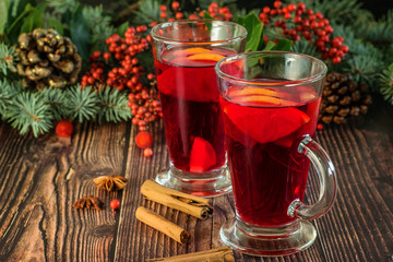 Traditional Christmas hot drink Mulled wine on the wooden background. Decoration of holidays vignette of branches of blue fir, red berries and pinecones.