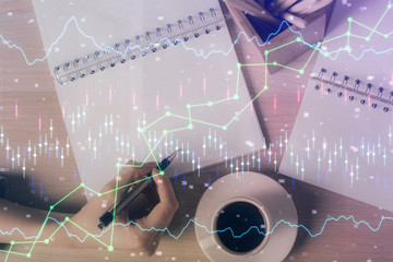 Multi exposure of hands making notes with forex chart huds. Stock market concept.