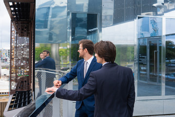 Confident business men talking in front of modern office building. Businessman and his colleague. Banking and financial market.