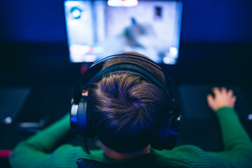 Professional gamer playing online games tournaments pc computer with headphones, Blurred red and...