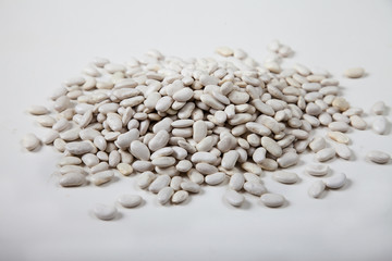 White raw beans sprinkled on a white background.