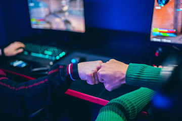 Professional gamer greeting and support team fists hands online game in neon color blur background. Soft focus, back view © Parilov