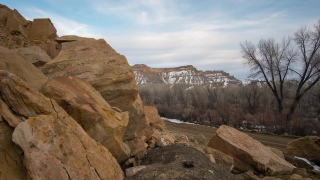 Timelapse of clouds moving through the desert in Utah moving across red rocks and boulders on a slider in the evening.