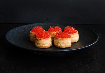 Tartlets with red caviar on a dark background. Festive snack for the buffet.