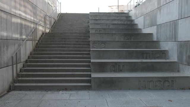Two concrete staircases, one with regular sized steps and one with giant steps, German language; slow pan up