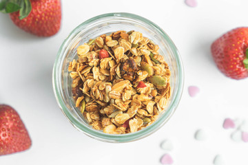 top view healthy granola in glass clear bottle with copy space and fresh strawberry in background