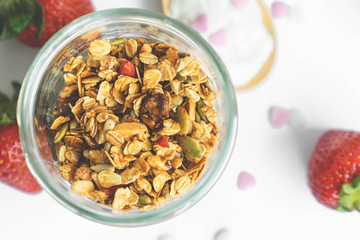 top view healthy granola in glass clear bottle with copy space and fresh strawberry in background