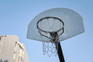 Outdoor basketball hoop with blue sky and building in the background © Formatoriginal