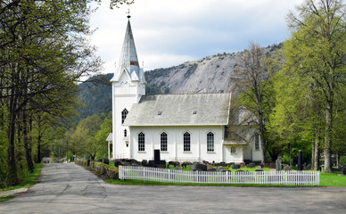 Old white public church in spring whith montain in the background.