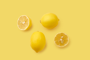 Overhead image with whole lemons and lemon slices on yellow background. Monochromatic concept. Copy space