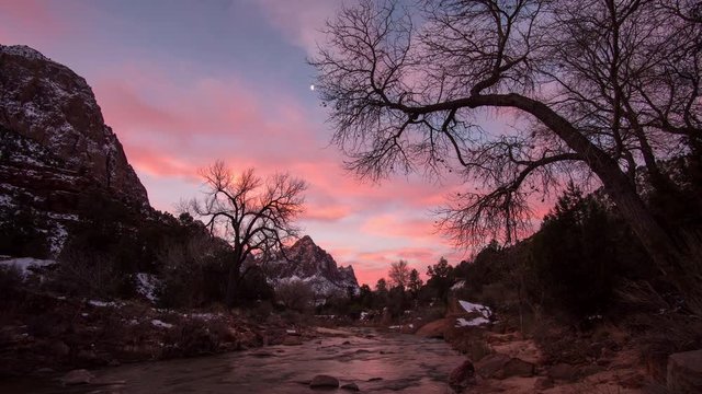 Timelapse of colorful sunrise in Zion looking down the Virgin River towards The Watchman peak as the clouds light up pink.