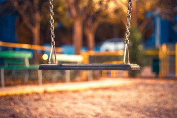 An empty  swin hang at the playground. No children are playing on the swing set, which is not moving. The swings are clean and well maintained. Back to School. Recess equipment. Outdoors. - Powered by Adobe