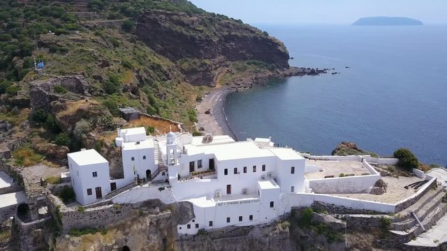 Aerial shot of church and white town on Kos island in Greece. Shot of a drone on a church on a hill. Rotating shot around church on hill.