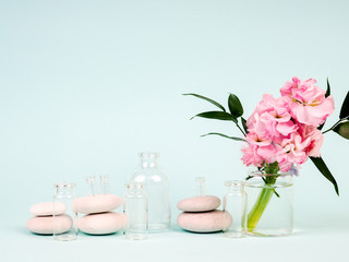 pink flowers in a vase, next to the Zen stones, tubes of oils, the theme of Spa and relaxation