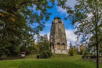 Zelena hora, Pelhrimov / Czech Republic - September 13 2019: Bismarck tower made of stone built in 19th century standing on a hill close to Cheb surrounded with green trees. Sunny day with blue sky. 