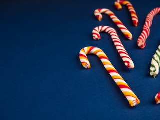 Christmas candy cane. On classic blue background. Flat lay. Christmas composition. A fan of caramel striped cane candies on a dark blue background. Minimalist New Year concept for your mockup.