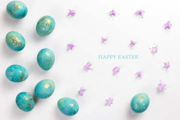 Fototapeta na wymiar Happy easter card. Stylish minimalistic composition of turquoise with gold easter eggs on a white background. Delicate spring flowers. Flat lay, top view, copy space.