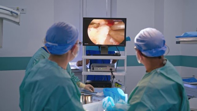 Operating process on the screen of a computer. Surgeons use a tool with camera while performing a surgery on a patient. Medical concept.
