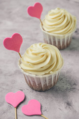 close up cupcakes with pink hearts on a gray concrete table copy space