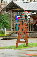 Texas miniature sized windmill with Texas flag and star on wind fan in front of a house with giant rustic star near the 