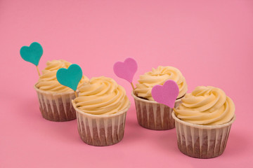 cute cupcakes decorated with pink and blue hearts on a pastel pink  background