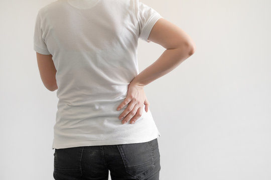 Close-up view of caucasian woman with pain in kidneys isolated on a white background. Girl with backache clasping her hand to her lower back. Woman suffering from ribbing pain.