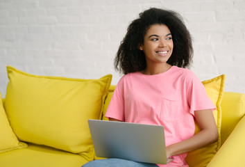 Happy emotional student studying, learning language, exam preparation sitting on yellow sofa....