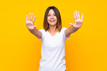 Young woman over isolated yellow background counting ten with fingers