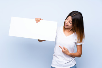 Young woman over isolated blue background holding an empty white placard for insert a concept