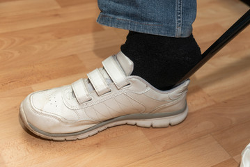 Einstieg in wei&szlig;en Sportschuh mit Hilfe eines Schuhanziehers