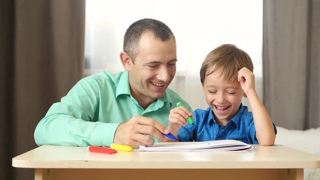 Happy dad spends time playing and drawing with his little son.