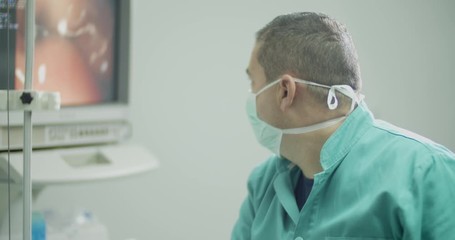 Portrait of male doctor specialist while doing colonoscopy procedure in the office room.