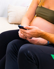 pregnant mom consulting her cell phone with her partner