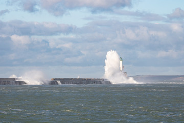 Fototapeta na wymiar Vague sur la digue Carnot et le phare de Boulogne-sur-Mer