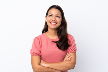 Young Colombian girl over isolated white background looking up while smiling