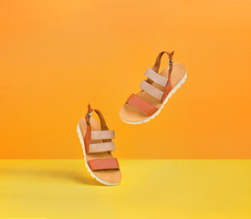 a pair of dancing yellow female leather sandals on a yellow-orange background for a banner with a...
