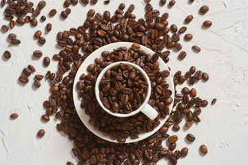 small white espresso Cup with coffee beans on white concrete table top view. 