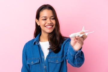 Young Colombian girl holding a toy airplane over isolated background