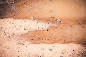 Deep spring puddle on the sandy road due to melting snow after winter.