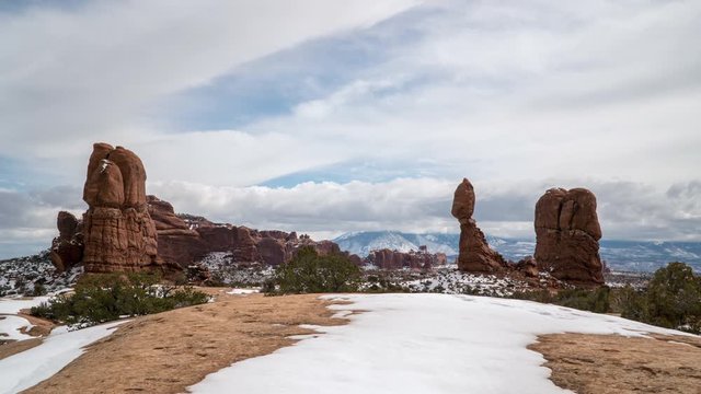Timelapse of clouds moving past Balanced Rock in winter looking towards the La Sal Mountains in the Utah desert.